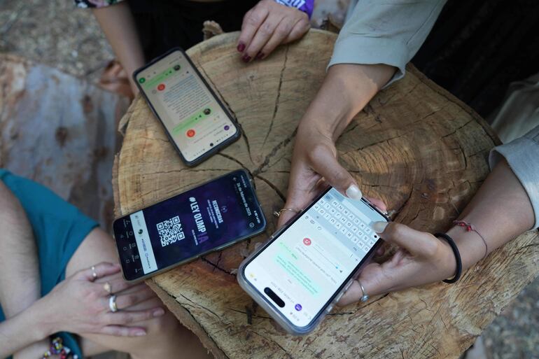 Miembros de la Red de Defensoras Digitales del movimiento Ley Olimpia, Vania Sisai Rodríguez, Marcela Hernández y Salma Semiramis, muestran cómo funciona la plataforma OlimpIA en su teléfono durante una entrevista con la AFP en Ciudad de México.