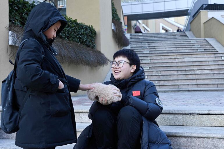 Zhang Yachun (derecha) habla con un niño interesado en su robot impulsado por inteligencia artificial llamado Aluo, en un centro comercial de Pekín.