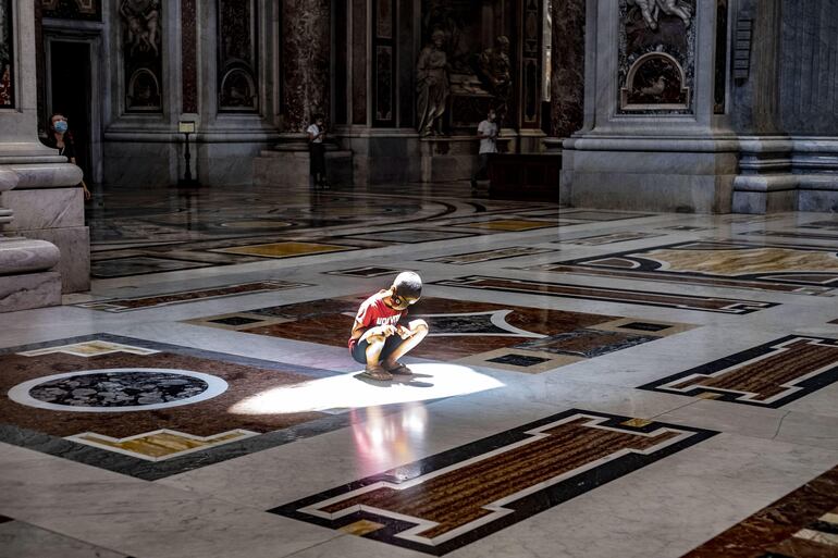 Un niño se agacha para observar su propia sombra en la basílica de San Pedro, en el Vaticano.