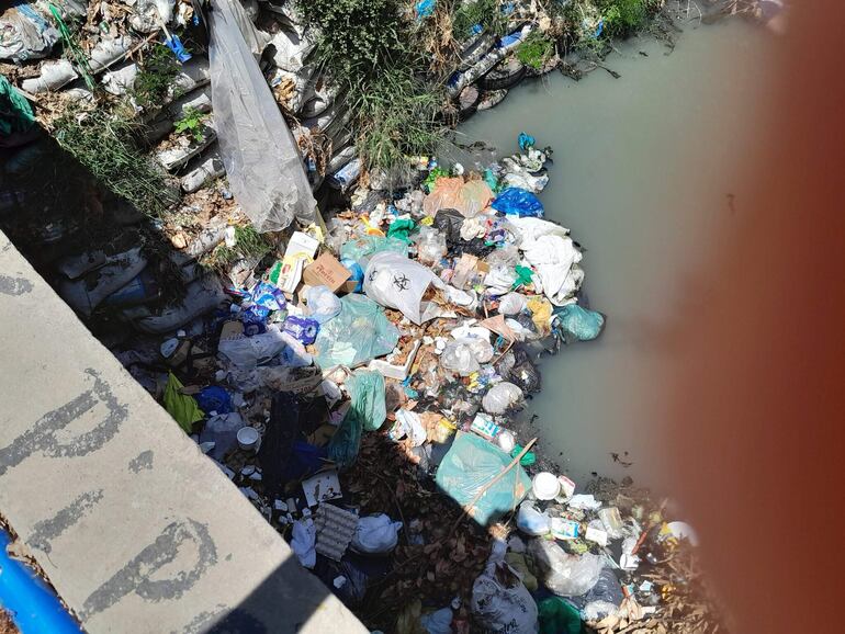 En el arroyo se observa una bolsa con el símbolo de basura patológica, aunque el contenido es difícil de determinar.