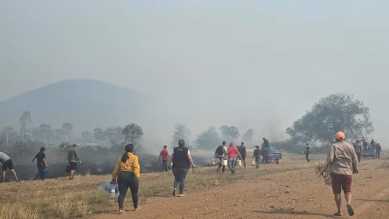 Los habitantes del centro urbano de Fuerte Olimpo, con ayuda de baldes, procuran sofocar los focos de fuego.  