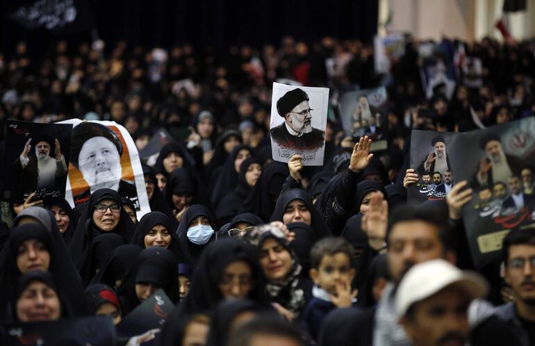 Los iraníes sostienen carteles del difunto presidente Ebrahim Raisi mientras lloran durante la ceremonia de procesiones fúnebres en la mezquita Mossallah en Teherán, Irán.