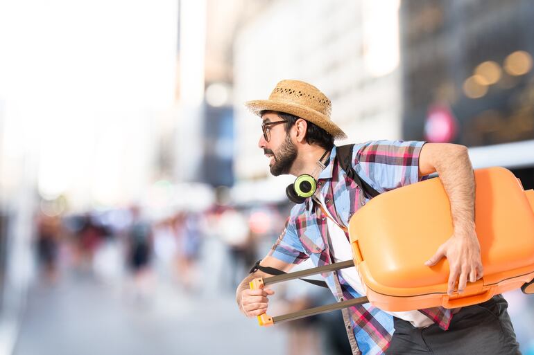 Turista corriendo con su maleta bajo el brazo.