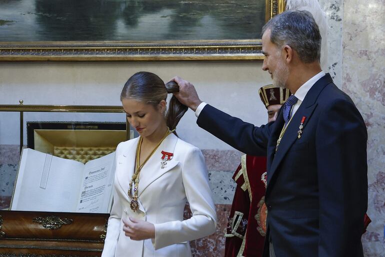 La princesa Leonor es ayudada por su padre, el rey de España, Felipe VI, tras serle impuestas las Medallas del Congreso y Senado en el escritorio del Congreso tras jurar la Constitución. (EFE/Chema Moya)
