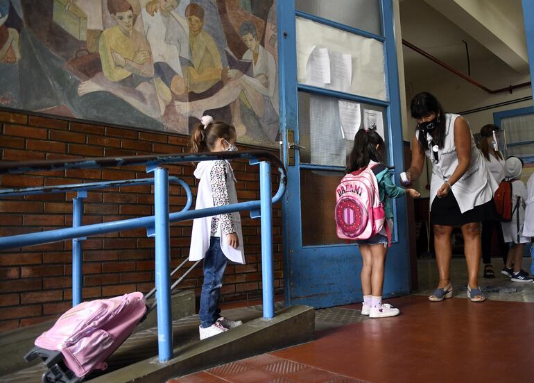 Alumnas de un colegio de Buenos Aires hace fila para que se les tome la temperatura antes de entrar a clases.