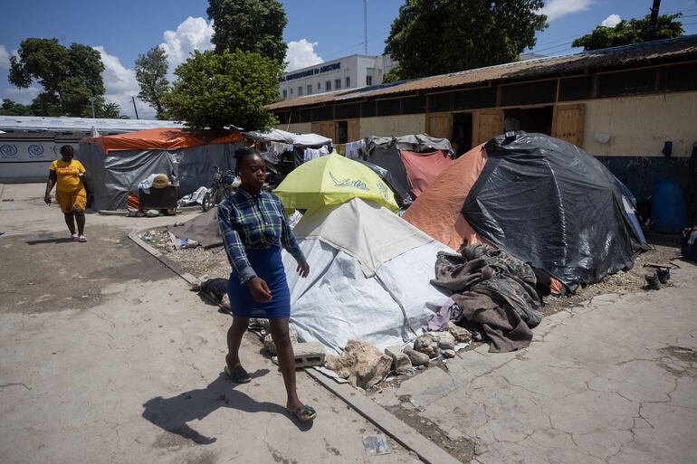Mujeres caminan por el campamento de refugiados Carrade, este sábado en Puerto Príncipe (Haití). Unas 3.000 personas que tuvieron que huir de sus casas por la violencia conviven en un campamento de refugiados no lejos de la embajada de Estados Unidos en Puerto Príncipe.
