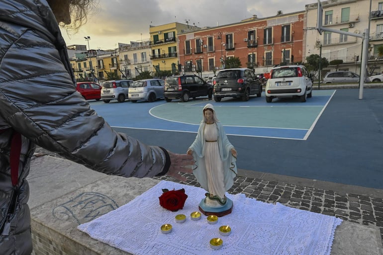 Un fiel reza el rosario frente a una estatua de la Virgen en la cancha de baloncesto del paseo marítimo de Pertini en Pozzuoli, cerca de Nápoles, Italia. La ciudad de Pozzuoli está cerca del epicentro de los terremotos registrados en los últimos días en la caldera volcánica de Campi Flegrei, cerca de Nápoles. 