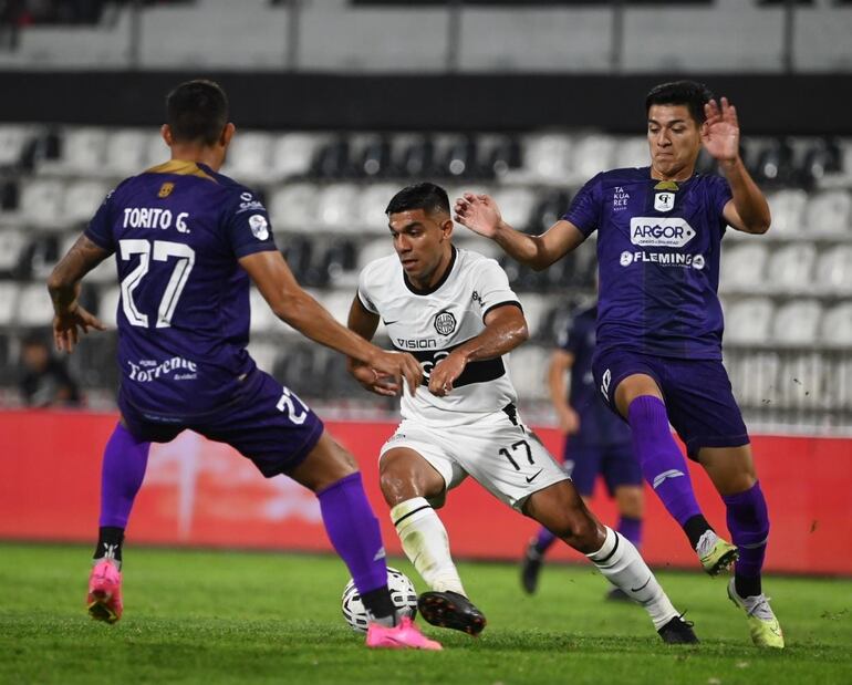 Marcos Gómez, jugador de Olimpia, pelea por el balón entre dos futbolistas de Tacuary por la primera fecha del torneo Clausura 2023 del fútbol paraguayo en el estadio Manuel Ferreira, en Asunción.