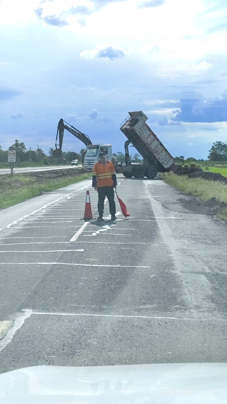 Los usuarios deben usar la carretera vieja, tras el cierre de la nueva ruta en un tramo de unos 100 km. En esta foto se puede ver a un obrero señalizando con un cono a los transeúntes de la vieja carretera.