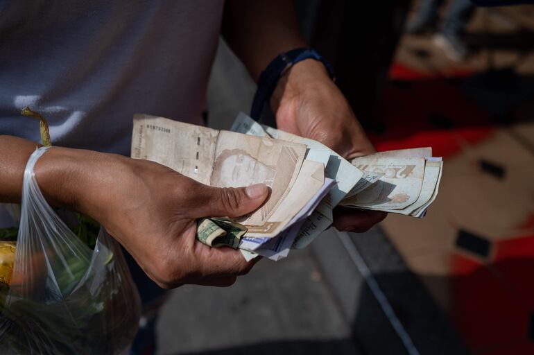 Una mujer cuenta bolívares en las calles de Venezuela.