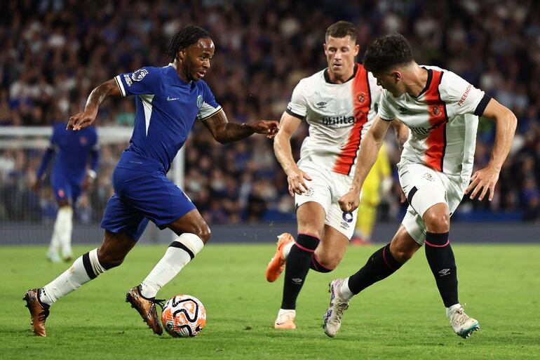 Raheem Sterling domina el balón ante la marca de dos jugadores del Luton Town, Ross Barkley y Ryan Giles, durante el partido que Chelsea ganó ayer 3-0.