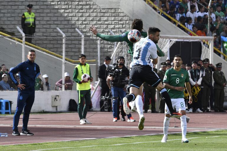 El entrenador argentino Lionel Scaloni (izq.) mira mientras el defensor argentino Nicolás Tagliafico (der.) y el mediocampista boliviano Gabriel Villamil (arriba) saltan al balón durante el partido de fútbol de las Eliminatorias Sudamericanas para la Copa Mundial de la FIFA 2026 entre Argentina y Ecuador, en el estadio Mas Monumental de Buenos Aires, a 7 de septiembre de 2023.