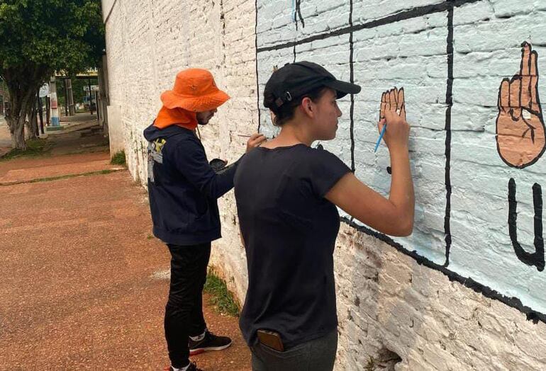 Unos 30 jóvenes que integran el Rotaract Club de Capiatá se unieron para pintar un mural del abecedario dactilológico en la muralla lateral del Centro Social y Cultural Capiateño