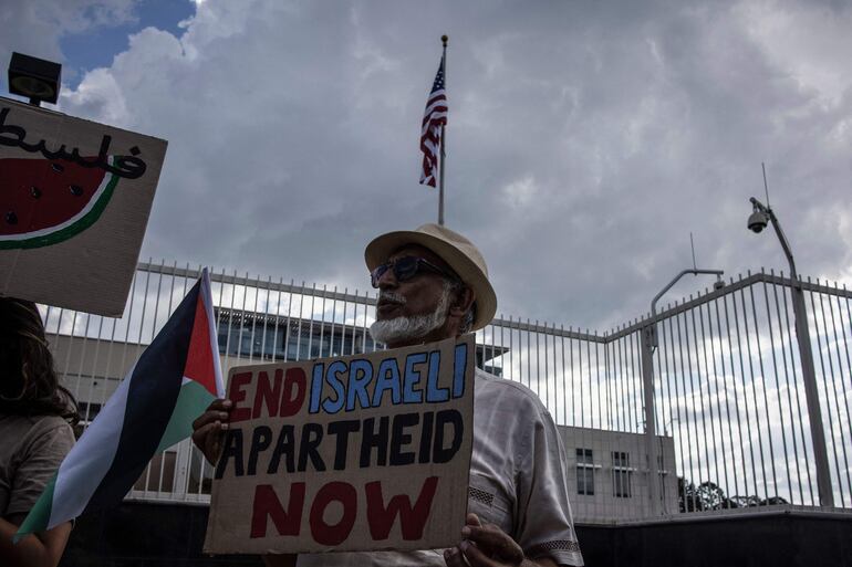 Pro-Palestinian activists hold banners and flags as they demonstrate following the International Court of Justice (ICJ) ruling of the case against Israel brought by South Africa in The Hague at the U.S. Consulate in Johannesburg on January 26, 2024. South African lawyers presented their case at the UN's top court in The Hague, where South Africa lodged an urgent appeal to force Israel to "immediately suspend" its military operations in Gaza. The International Court of Justice (ICJ) ruled on January 26, 2024 that it has jurisdiction over the genocide case. (Photo by DAVIDE LONGARI / AFP)