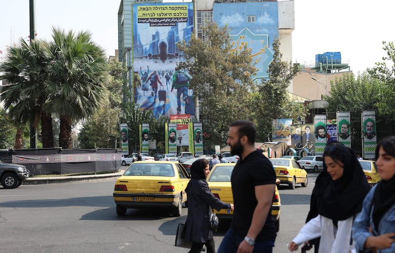 Los iraníes pasan junto a un cartel antiisraelí con una frase en persa y hebreo: "Israel ya no es un lugar seguro para vivir" en la Plaza Palestina en Teherán, Irán, 16 de octubre de 2024. El plan de Israel para responder al ataque iraní del pasado 1 de octubre “ya está listo”, informó este miércoles la cadena CNN, que cita a una fuente conocedora del asunto.