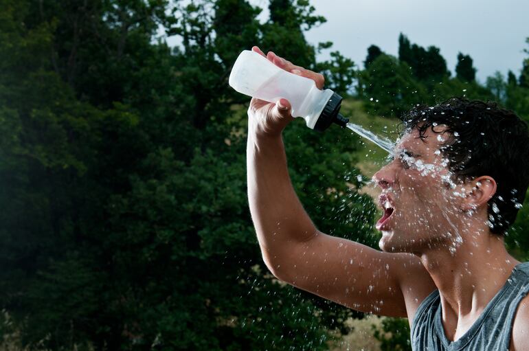 Un hombre se refresca durante una sesión de ejercicio al aire libre.