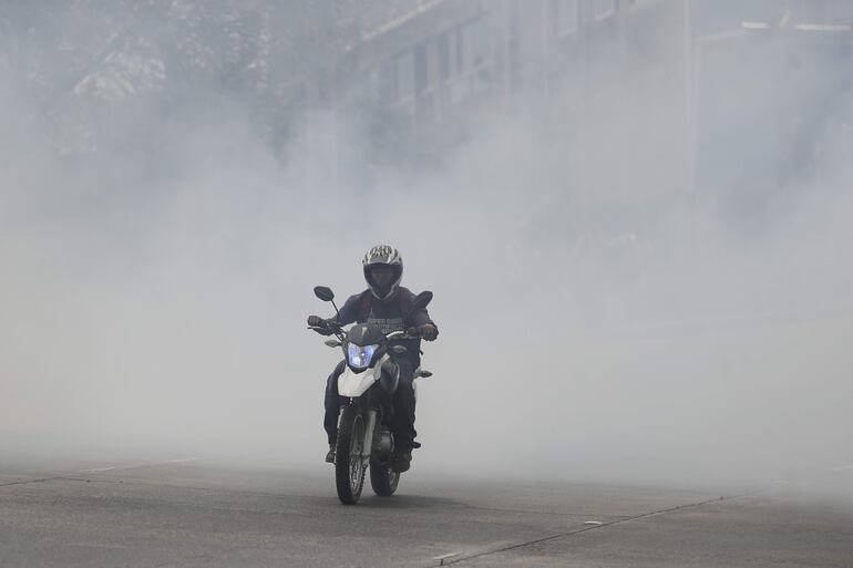 Un hombre en motocicleta transita por una avenida cubierta de humo, este martes en Tegucigalpa (Honduras).