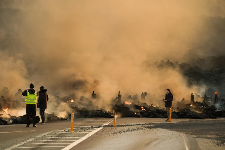 Imagen ilustrativa: trabajadores de los medios de comunicación junto a un flujo de lava durante una erupción volcánica cerca de Grindavik, península de Reykjanes, Islandia.