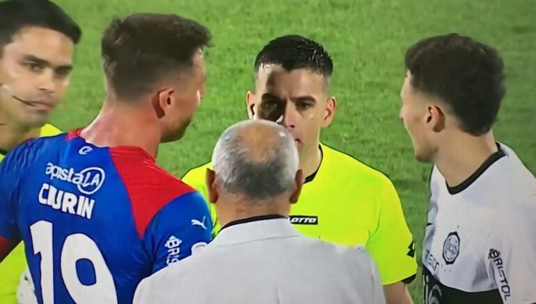 El argentino Diego Churín (i), delantero de Cerro Porteño, junto a Francisco Arce (centro hacia abajo) y Facundo Bruera (d), ambos de Olimpia, conversan con el árbitro Derlis López después de final el superclásico del fútbol paraguayo en La Nueva Olla.