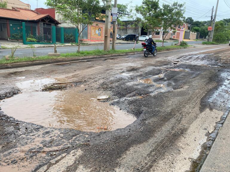 Muestra baches inundados tras las lluvias, obligando a conductores de motos y automóviles a maniobrar con precaución para evitar daños y accidentes.