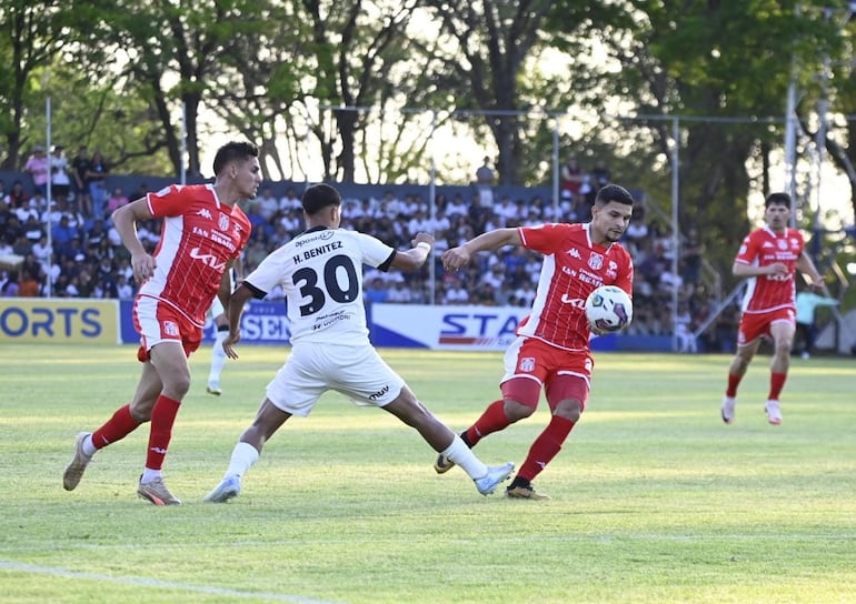 Hugo Adrián Benítez pelea por el balón con los defensores de General Caballero