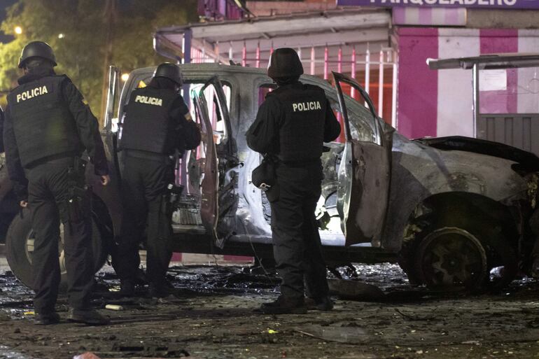 Policías investigan los restos de un carro bomba que explotó en la madrugada de hoy en los exteriores del edificio del Servicio Nacional de Atención Integral a Personas Privadas de Libertad (SNAI), en Quito (Ecuador).  (EFE)