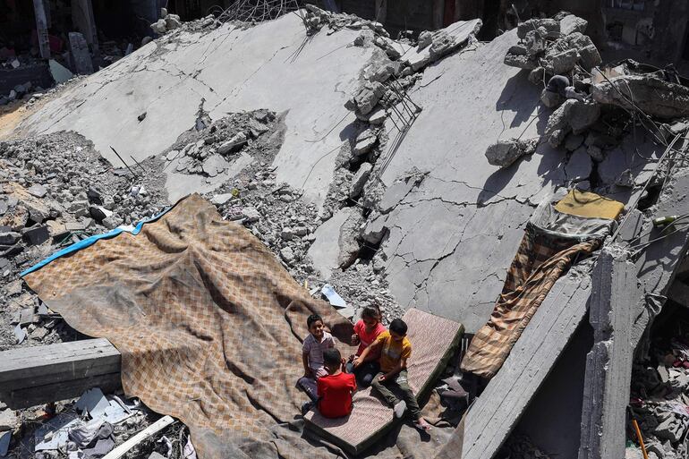 Niños descansan entre los escombros de un edificio destruido por ataques israelies, este sábado en Nuseirat, en el centro de la Franja de Gaza.
