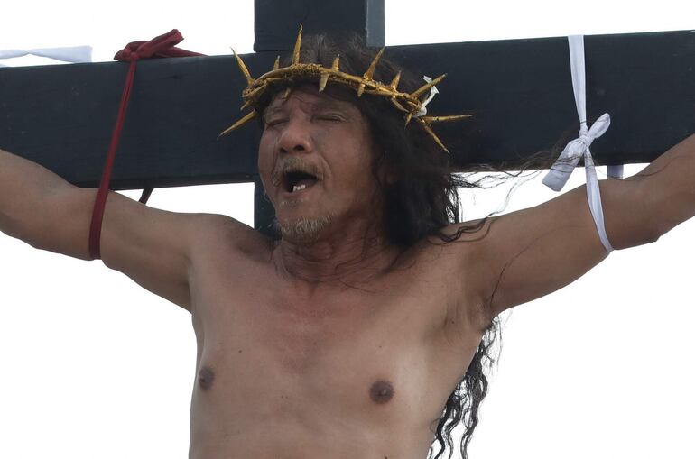 Ruben Enaje, quien representa a Jesucristo, es clavado a una cruz de madera durante la representación de la crucifixión de Jesucristo en el VIernes Santo.