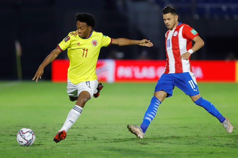 Ángel Romero (d), jugador de la selección paraguaya, disputa el balón con Juan Guillermo Cuadrado en un partido de las Eliminatorias Sudamericanas al Mundial Qatar 2022 en el estadio Defensores del Chaco, en Asunción.
