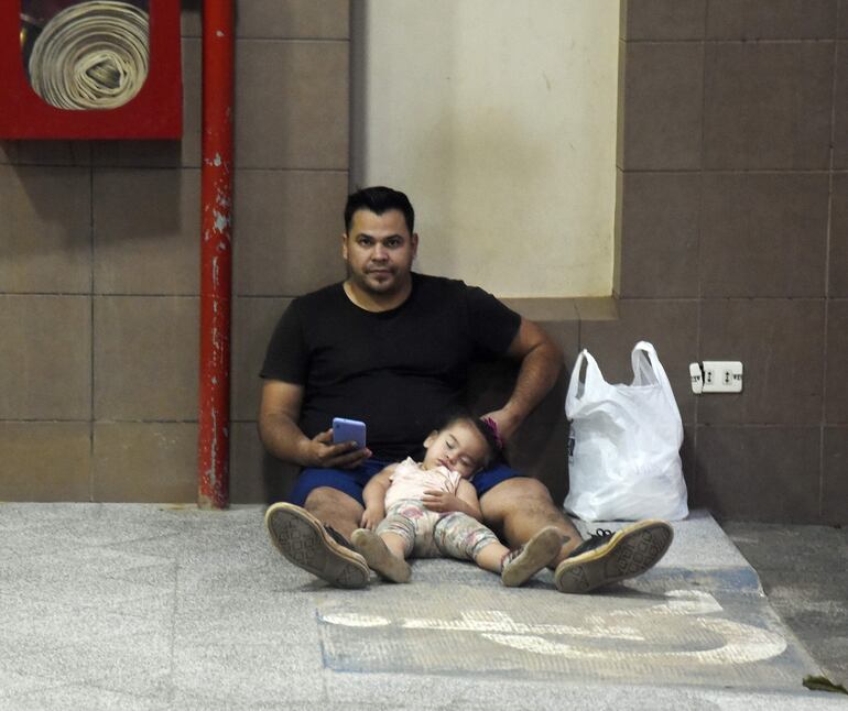 Un padre al cuidado de su esposa que espera dar a luz, mostró la bolsa de insumos y medicamentos adquiridos de la farmacia. También está al cuidado de su pequeña hija, quien cansada de jugar se quedó dormida. 