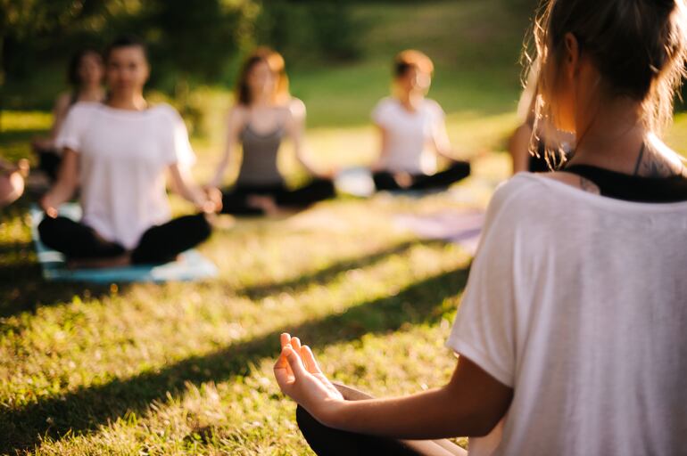 Un grupo de mujeres jóvenes practica yoga al aire libre.