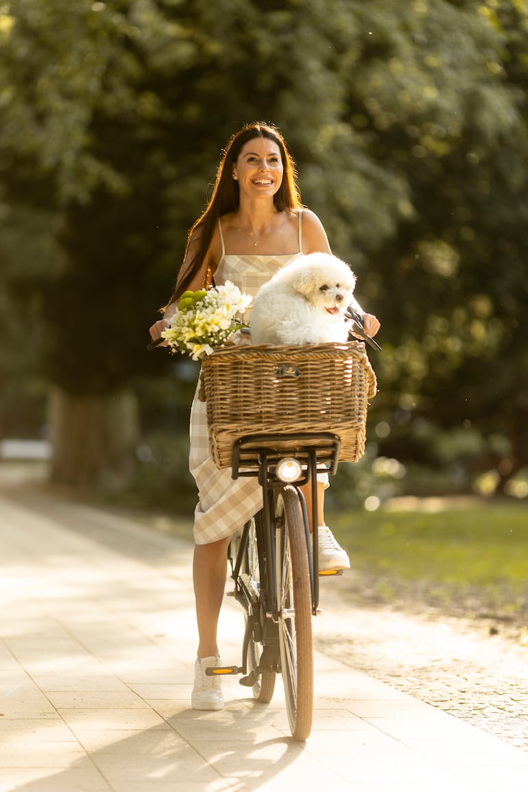 Una joven bonita en paseo en bici con su mascota con el atuendo ideal para la temporada.