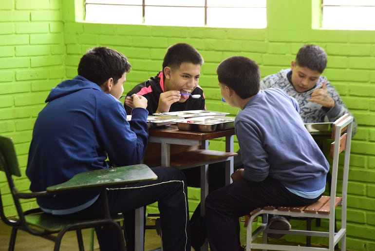 Estudiantes comparten mesa para no almorzar sobre los pupitres.