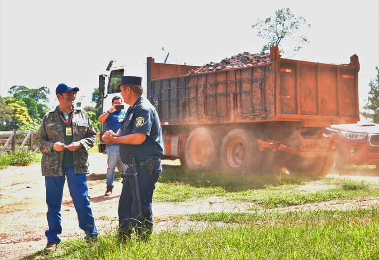 Momento en que un camión tumba llevaba un cargamento de tierra extraído de la segunda cantera allanada, pasando al costado de uno de los técnicos del Mades y un oficial de policía.