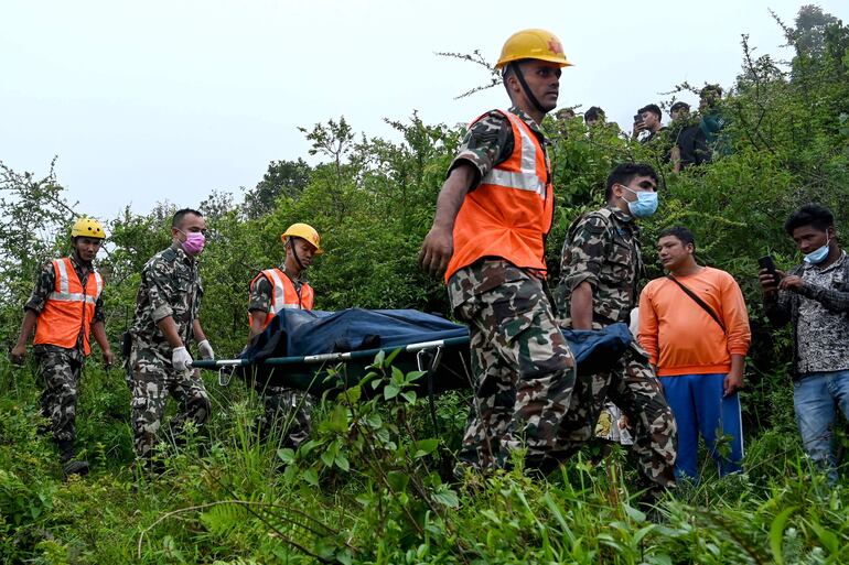 Rescatistas trasladan el cuerpo de una de las personas fallecidas en un accidente de helicópero ocurrido el pasado miércoles en las afueras de Katmandú, Nepal.