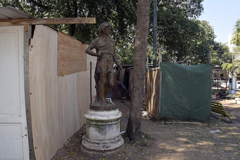 La escultura "posa" entre casitas de terciadas, baños portátiles, cloaca y basura. Se trata de "El verano", figura neoclásica de un adolescente joven que representa el verano, con el cuerpo ágil y trajes antiguo. Todo esto se refiere al trabajo de la cosecha.