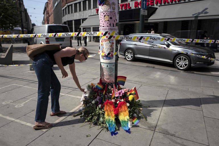 Una mujer deposita flores en un improvisado memorial en la escena del crimen. 