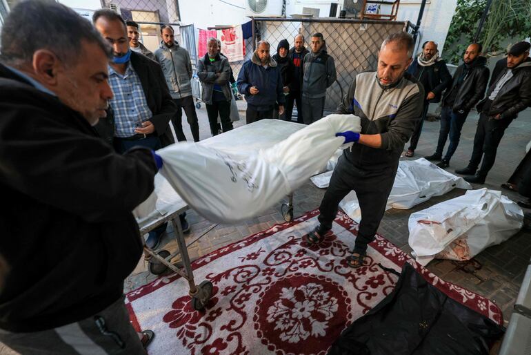 Trabajadores médicos mueven un cuerpo de una persona fallecida durante un bombardeo israelí, fuera del hospital al-Najjar de Rafah, en el sur de la Franja de Gaza, este lunes.