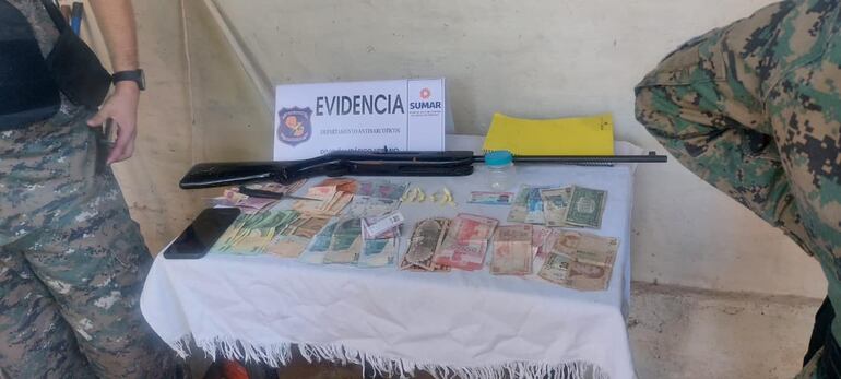 evidencias en una mesa. Dinero en efectivo, escopeta