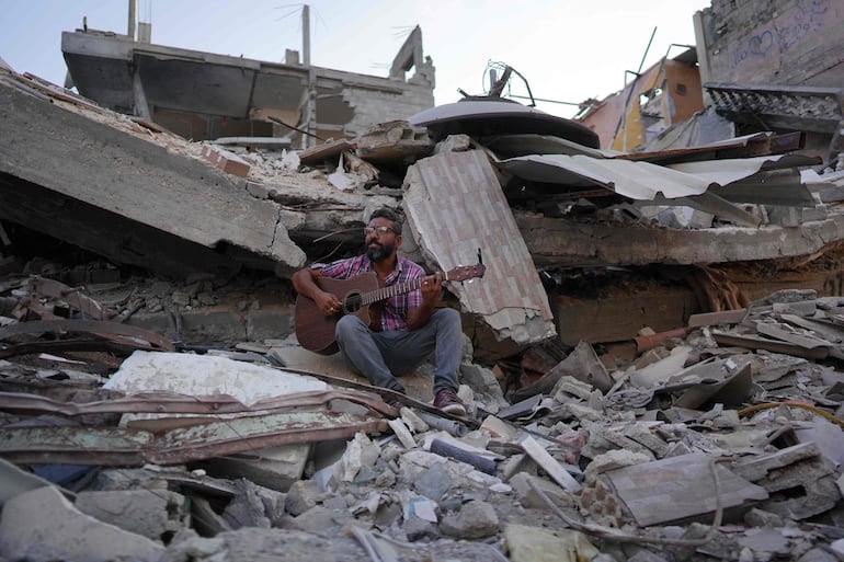 Un músico toca la guitarra entre los escombros de edificios destruidos, el domingo  en Jan Yunis, en el sur de la Franja de Gaza.