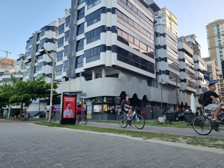 Ciclistas en bicicleta pedalean frente al mar por la bicisenda de Itapema, Santa Catarina.