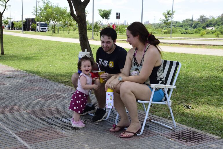 Una familia aprovecha la sombra de un árbol en el paseo central de la Avenida Costanera para disfrutar de un tereré.