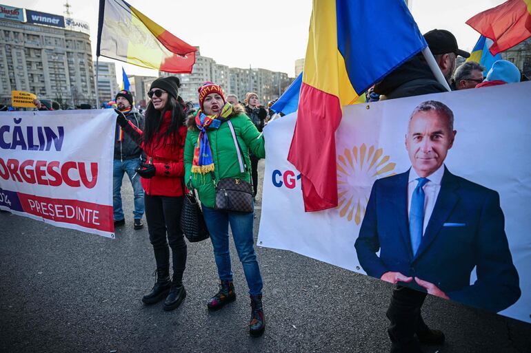 Los manifestantes sostienen una pancarta con la imagen del candidato presidencial Calin Georgescu frente al edificio del gobierno rumano en Bucarest.