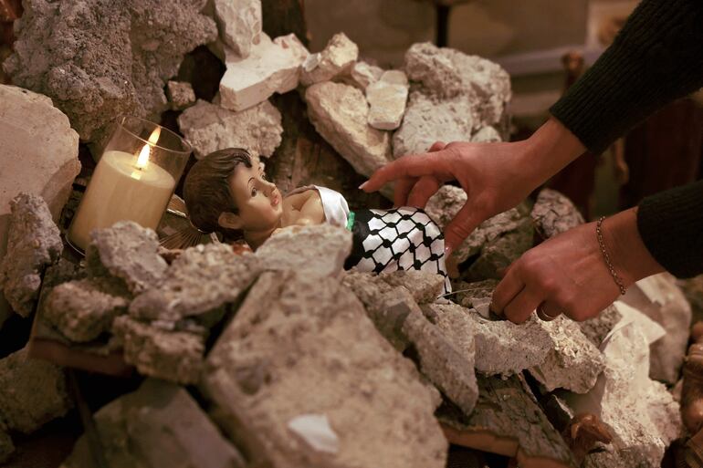 Una mujer instala una imagen del Niño Jesús entre escombros, en referencia a la guerra en Gaza, en la Iglesia Evangélica Luterana de Belén, en Cisjordania.