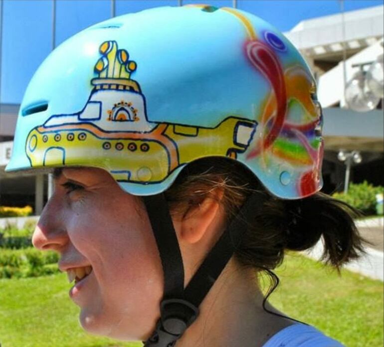 Una ciclista con un casco customizado con motivos de Yellow Submarine se detiene frente a la Municipalidad de Asunción.