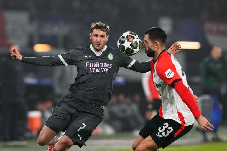 AC Milan's Mexican forward #07 Santiago Gimenez (L) fights for the ball with Feyenoord's Slovakian defender #33 David Hancko   during the UEFA Champions League knockout phase play-off 1st leg football match between Feyenoord Rotterdam and AC Milan at the Stadion Feijenoord "De Kuip" in Rotterdam, on February 12, 2025. (Photo by JOHN THYS / AFP)