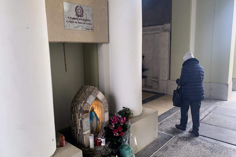 Una mujer pasa por delante de un altar dedicado a los "caídos por la covid-19" en el cementerio de la localidad italiana de Codogno, convertida hace cinco años en la 'zona cero' de Europa.