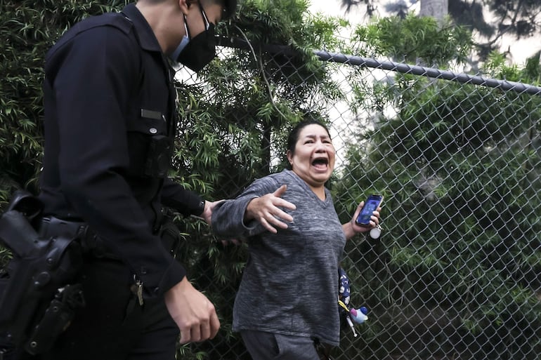 Una mujer reacciona mientras es evacuada por un agente de policía de un barrio amenazado por el incendio forestal de Palisades en Pacific Palisades, California, EE.UU., el 07 de enero de 2025.