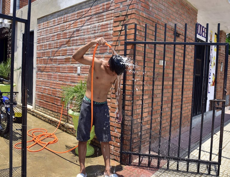 Joven se refresca con el agua de una manguera. Las temperaturas siguen altas, aunque ya no hay “ola de calor”.