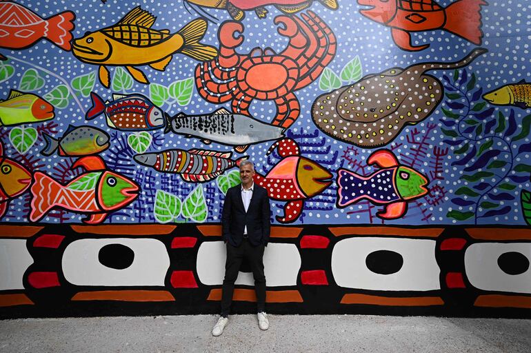 El curador de la Bienal de Venecia, el brasileño Adriano Pedrosa, posa frente a uno de los murales realizados para esta 60° edición.